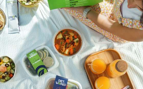 Diet World meal boxes and cold-pressed juice laid out for a picnic